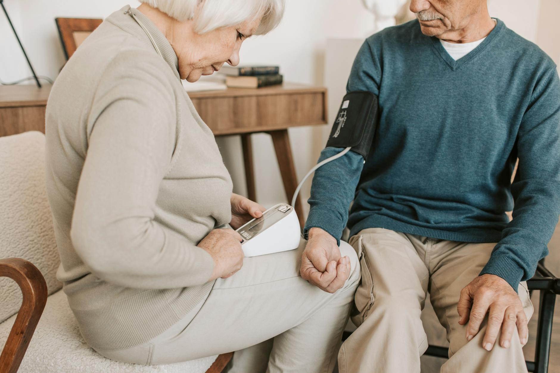 elderly woman checking the blood pressure of an elderly man